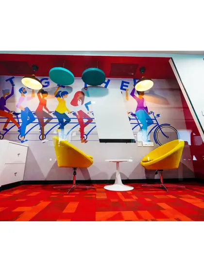 A whimsical breakout space at Mindsprint featuring a "Together" mural and bright yellow chairs. The reflective glass wall adds depth to the room, making it feel larger and more dynamic.