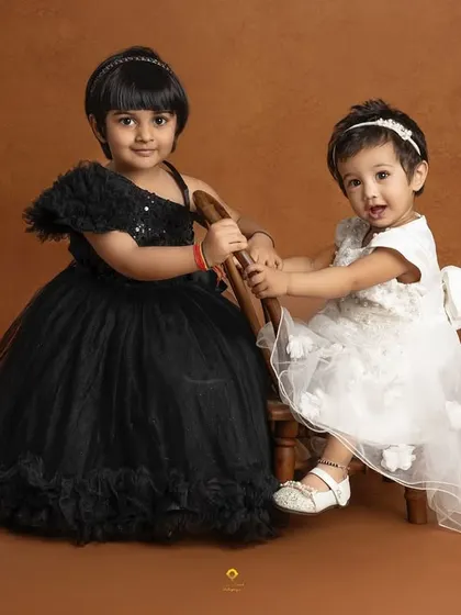 Two sisters, dressed in beautiful black and white gowns, share a playful moment. This image captures the unique bond and personalities of siblings.