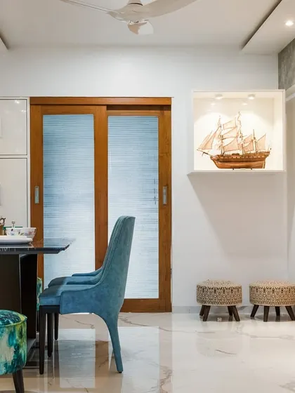 The dining area is simple yet elegant, with a sleek table, comfortable seating, and a beautiful ship model displayed in a lit niche, adding a personal touch.