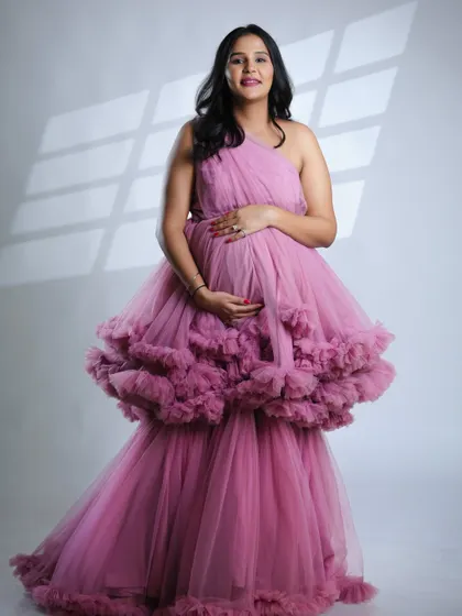 A full-length standing portrait in the pink gown. This pose is both elegant and empowering, celebrating the beauty of the pregnant form.