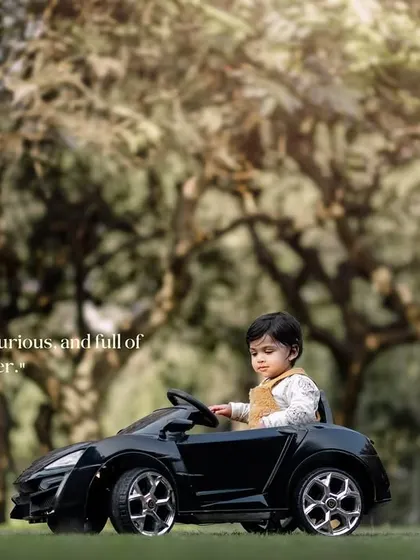 Cute, curious and full of cheer. A toddler takes a thoughtful pause from driving his toy car.