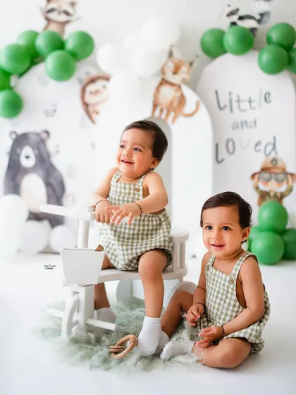 One twin rides the tricycle while the other looks on in this adorable twin birthday shoot.