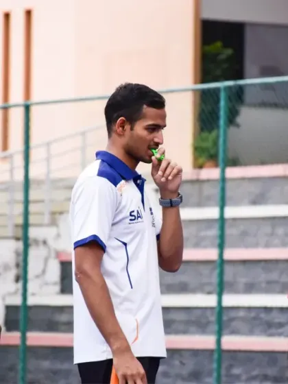 A coach observes the game from the sidelines, providing strategic guidance during the Interschool Basketball Tournament.