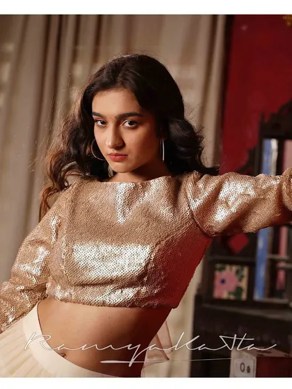 A confident portrait showcasing the all-over sequin work on the beige crop top. The modern cut and shimmering texture make it a party-ready piece.
