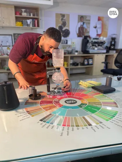 A student experimenting with a syphon coffee maker, a visually stunning brewing method that produces a uniquely clean cup.