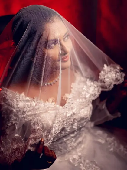 A classic Christian bridal portrait with the bride looking serene under her veil, captured with dramatic red lighting for a touch of glamour.
