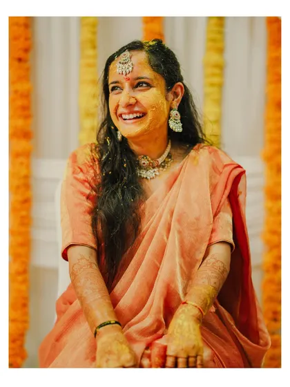 The bride's infectious laughter fills the frame as she enjoys her Haldi ceremony, her face glowing with happiness and turmeric.