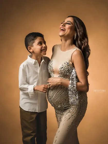 A moment of pure joy and laughter between a mother and son during her glamorous maternity shoot. His happy expression is priceless.