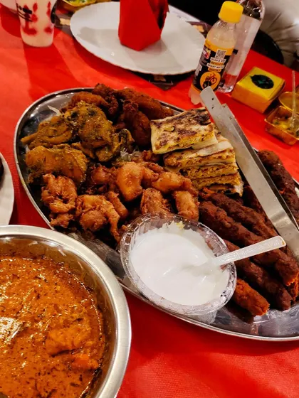 A complete starter setup with a platter of sheesh kebabs and fried items, alongside a bowl of rich, creamy curry and fresh raita. This is how I ensure your guests have a full-flavoured experience.