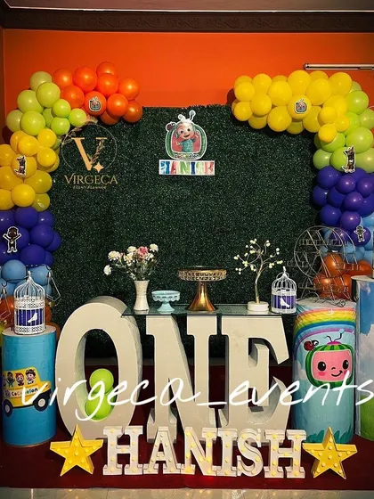 A Cocomelon first birthday setup with a lush green grass backdrop and a rainbow of colorful balloons. The large 'ONE' letters make a great photo opportunity.