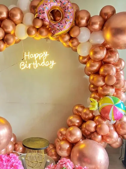 A close-up of the rose gold balloon arch, showing the fun donut and lollipop foil balloons. These little details are what make a themed birthday party feel complete and special.