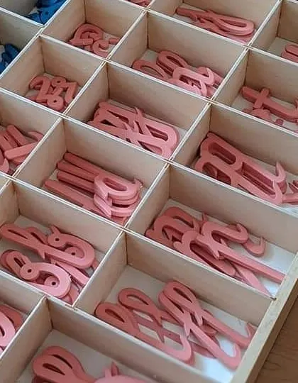 This is the Movable Alphabet, a fundamental tool for early literacy. By physically manipulating the cursive letters to form words, children learn to write before their hands are even ready to hold a pencil, connecting the sounds of language to their symbolic representation.