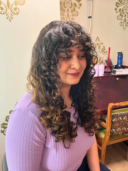 The curly bangs soften the look and draw attention to the eyes.