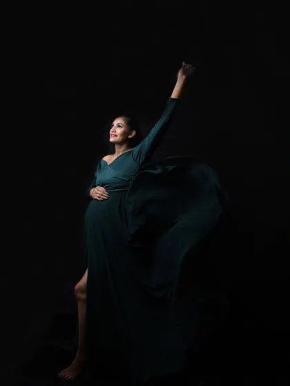 A powerful and dynamic pose in a dark green gown. The high slit and fabric movement add a sense of strength and confidence.