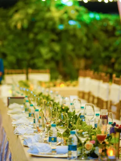 Another perspective of a beautifully arranged long table for an outdoor event, ready to welcome guests for an evening of delicious food and great company.