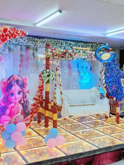 Another angle of the naming ceremony stage, highlighting the floral arch over the swing and the vibrant blue Christmas tree prop, adding a unique touch to the decor.