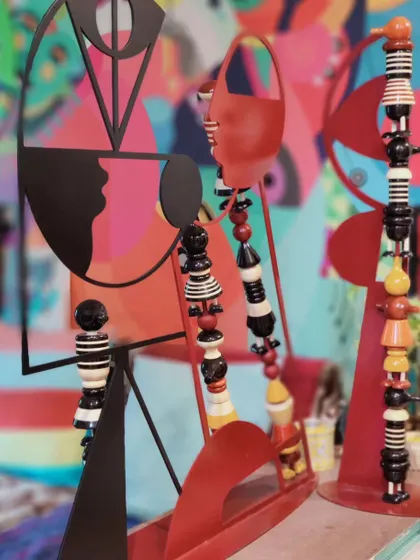 A close-up of our 'HYBRIDS' sculptures, which combine abstract metal silhouettes with colorful, hand-lacquered Channapatna wooden toy elements. This creates a fusion of contemporary sculpture and traditional Indian handicraft.