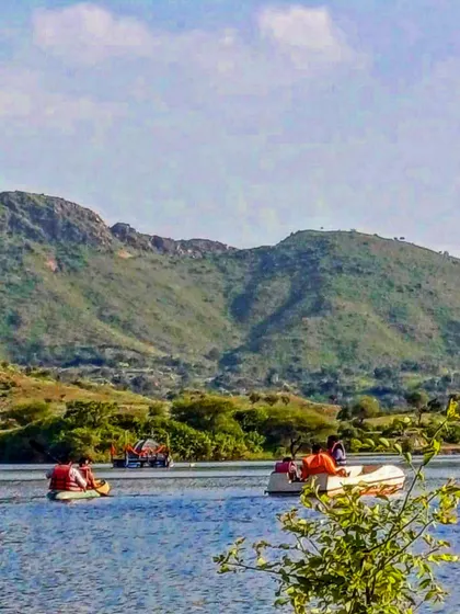 A wide shot of guests enjoying boating and kayaking activities on the lake. The beautiful green hills surrounding the water provide a stunning backdrop for a day of adventure.
