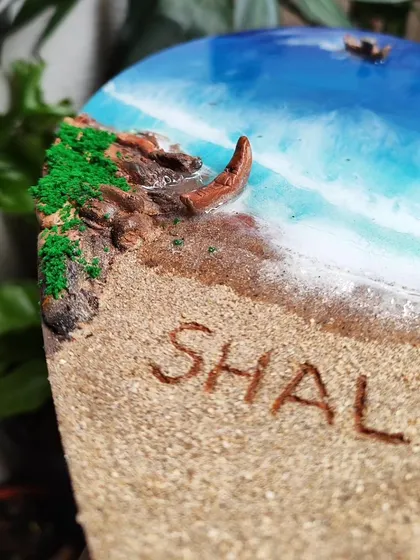 Detail of the name 'Shalini' written in the sand on the heart-shaped resin art.