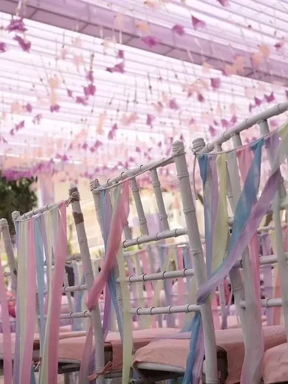 A whimsical detail of pastel-colored ribbons tied to the backs of chairs, adding a soft and dreamy touch to the decor.
