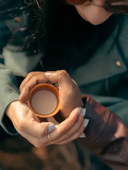 Love is sharing a warm cup of chai on a cool morning. This close-up focuses on their hands intertwined around a traditional clay cup, a simple and beautiful symbol of their bond.