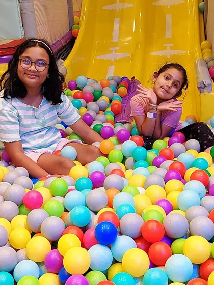 Friends enjoying the ball pit together after a trip down the slide.