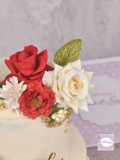 A close-up of the handmade red and white sugar flowers on the engagement cake.