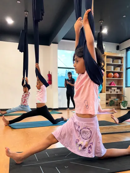 A group of young flyers practicing splits with the help of aerial hammocks. This shows how we can work on advanced flexibility in a fun, group setting.