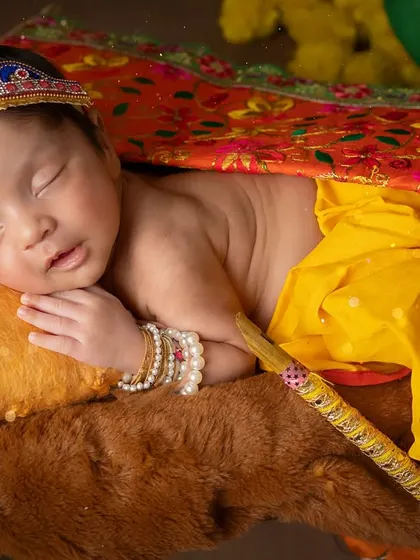 Peacefully dreaming. This pose showcases the baby's serene expression and the beautiful, traditional costume.