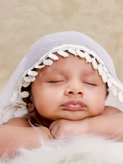 A close-up version of the lace veil portrait, focusing on the baby's peaceful expression and pouty lips.