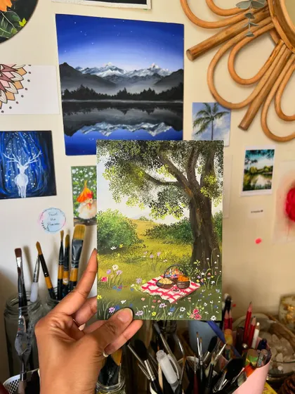 Holding the finished picnic painting in my studio. It’s a perfect little escape into a sunny, peaceful day.