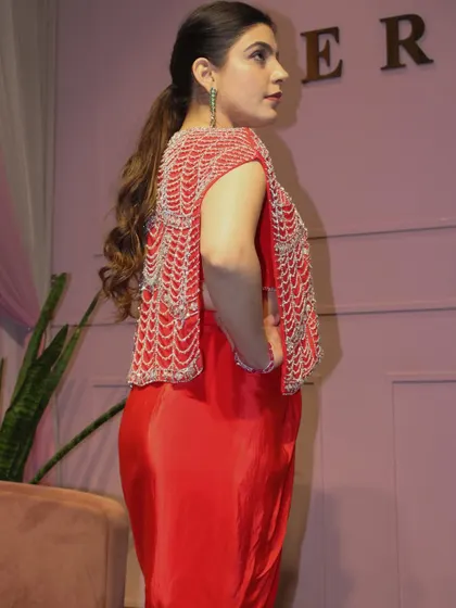 A side view of the red draped skirt set, showing the detail on the back of the jacket.