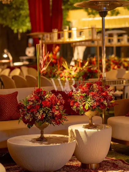 Detail of the lounge seating. The modern white tables are topped with brass urns filled with rich red roses, a simple yet elegant touch that ties into the overall red and gold theme.