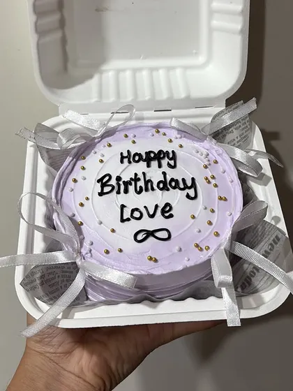 An elegant lavender bento cake for a loved one, decorated with delicate silver ribbons and golden sprinkles.