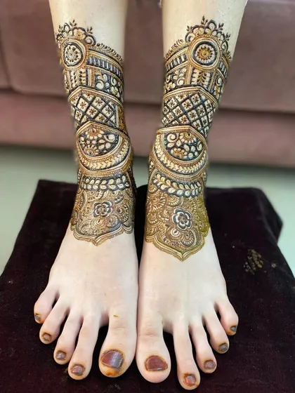 The leg mehendi design is now complete, with intricate bands of geometric and traditional patterns wrapping around the ankle.