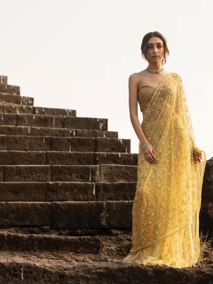 A majestic shot on the stone steps, with the golden saree catching the light beautifully.