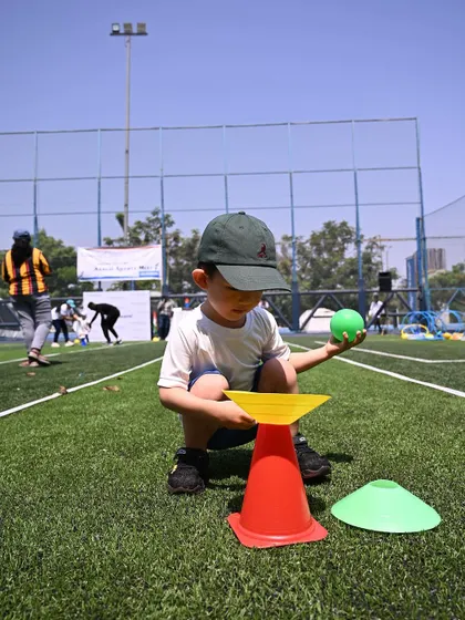 A child balances a ball on a cone, a task requiring great focus and stability.