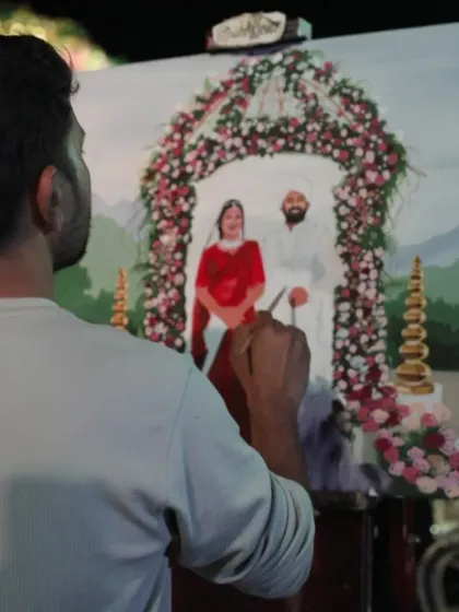 Adding the fine details to the bride's red lehenga. We work diligently through the event to complete the painting by the end.
