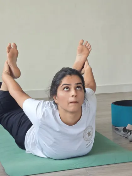A close-up of a student in Dhanurasana, her upward gaze reflecting the uplifting and energizing quality of this powerful backbend.