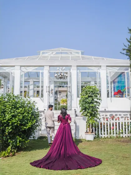 The couple walks hand-in-hand towards a magnificent glasshouse, with the bride's long purple gown trailing behind her. A shot straight out of a modern fairytale.
