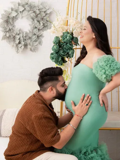 A moment of pure joy and anticipation. The father-to-be kisses the baby bump with a huge smile, while the mother-to-be laughs. It's a candid, heartwarming interaction.