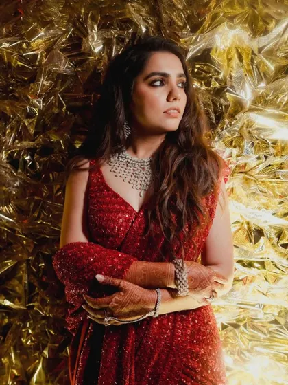 A portrait of the bride, exuding confidence and glamour in her red sequined outfit, perfectly complementing the golden Sangeet decor.