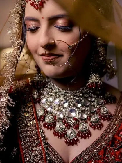 A beautiful close-up of a bride, her face gently veiled, highlighting her intricate jewelry and serene expression.