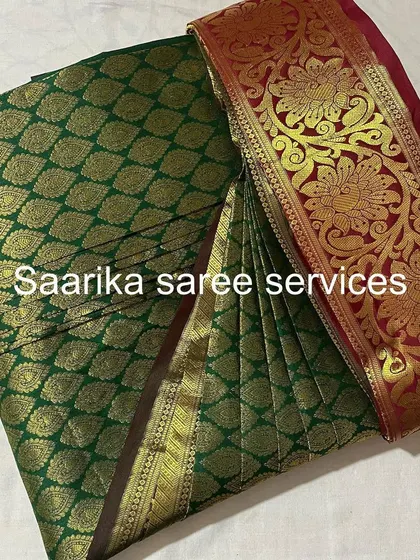 A rich green and red Kanjivaram saree, pleated and ready for a wedding. This service is a must for bridal trousseaus.