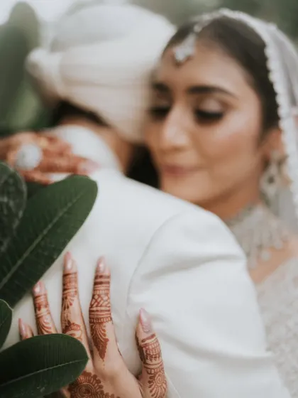 A close-up capturing the intricate henna on the bride's hands as she embraces her groom. These are the detailed, emotional moments we help create.