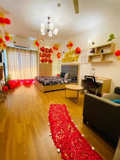 A romantic birthday or anniversary decoration for a spacious room, featuring a rose petal pathway, balloons, and "I Love You" and "Happy Birthday" foil letters.