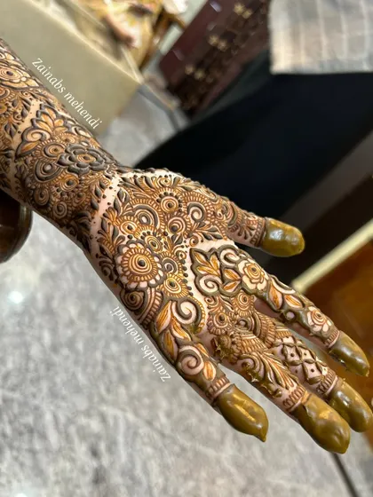 A full view of Zoya's hand and forearm, showcasing the complete engagement henna design.