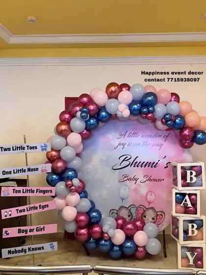 A fun and colorful baby shower setup with a balloon arch and cute signboards. The 'BABY' blocks and elephant-themed backdrop make it a cheerful setting for the celebration.