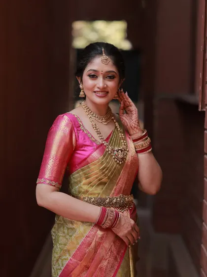 This bride is wearing a beautiful olive green and pink silk saree. I created a makeup look with a bold lip and defined eyes to match the richness of her outfit and traditional gold jewellery.