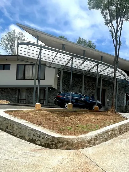 The winged roof of this Kotagiri home is a key feature, creating a dynamic silhouette against the sky. The use of natural stone for the lower level anchors the building firmly into the landscape.